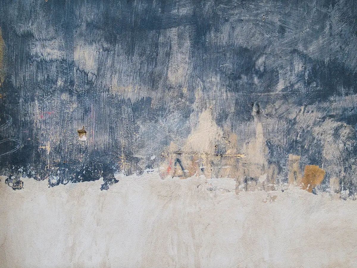 Vieux mur dont la peinture bleu ardoise s’écaille sur un enduit beige